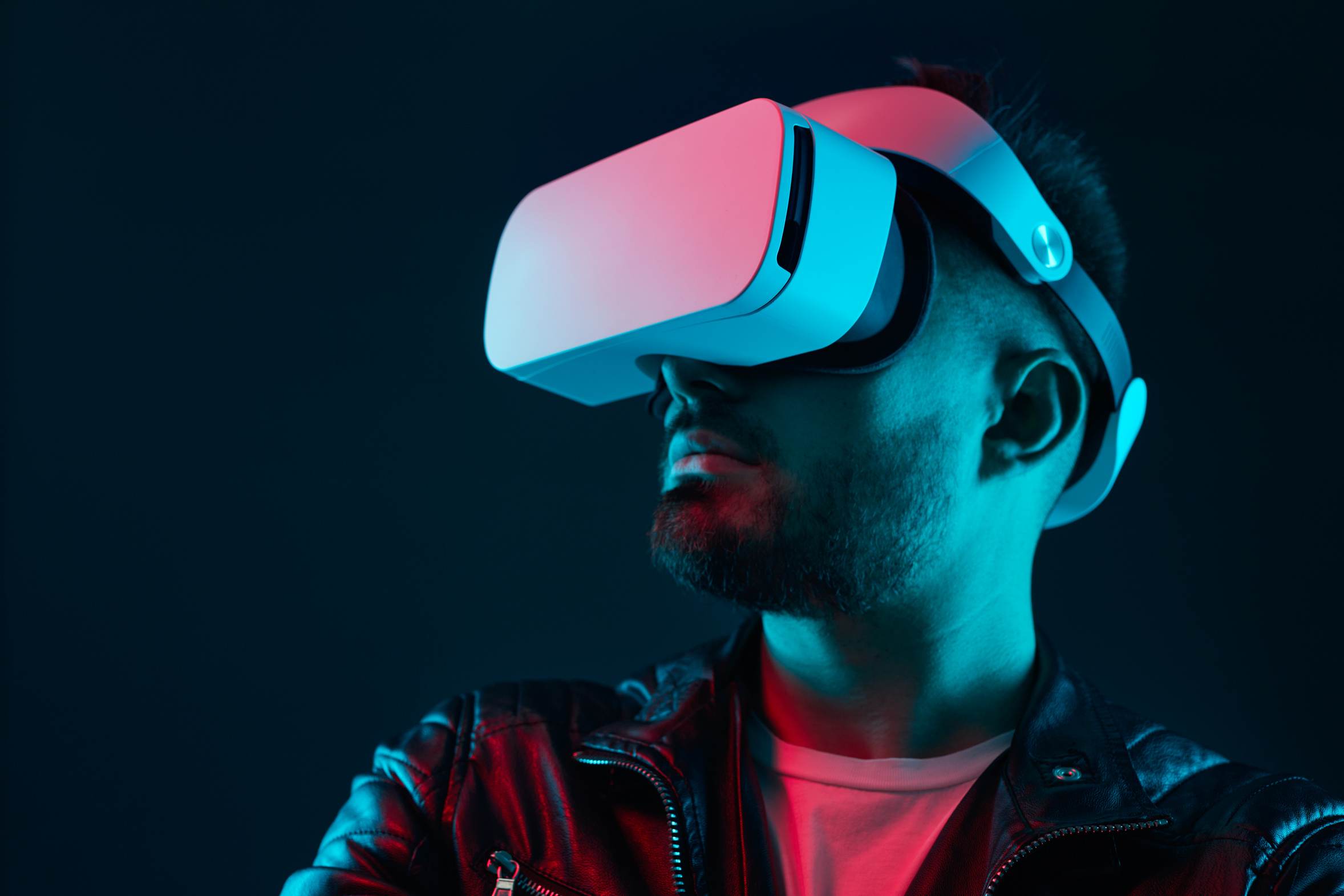 A person wearing a virtual reality headset in a dark room lit in teal and red.